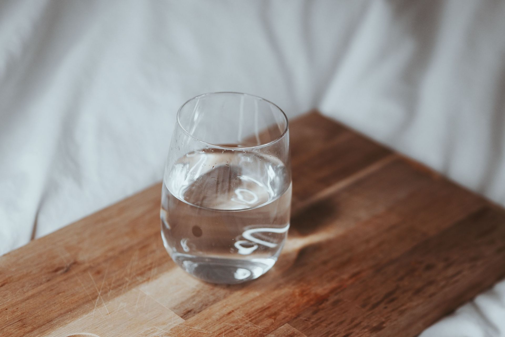 A refreshing glass of water placed on a wooden board, perfect for hydration.